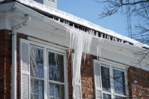 A massive icicle hangs from the edge of a roof damaging the gutters and spelling trouble for the homeowner.